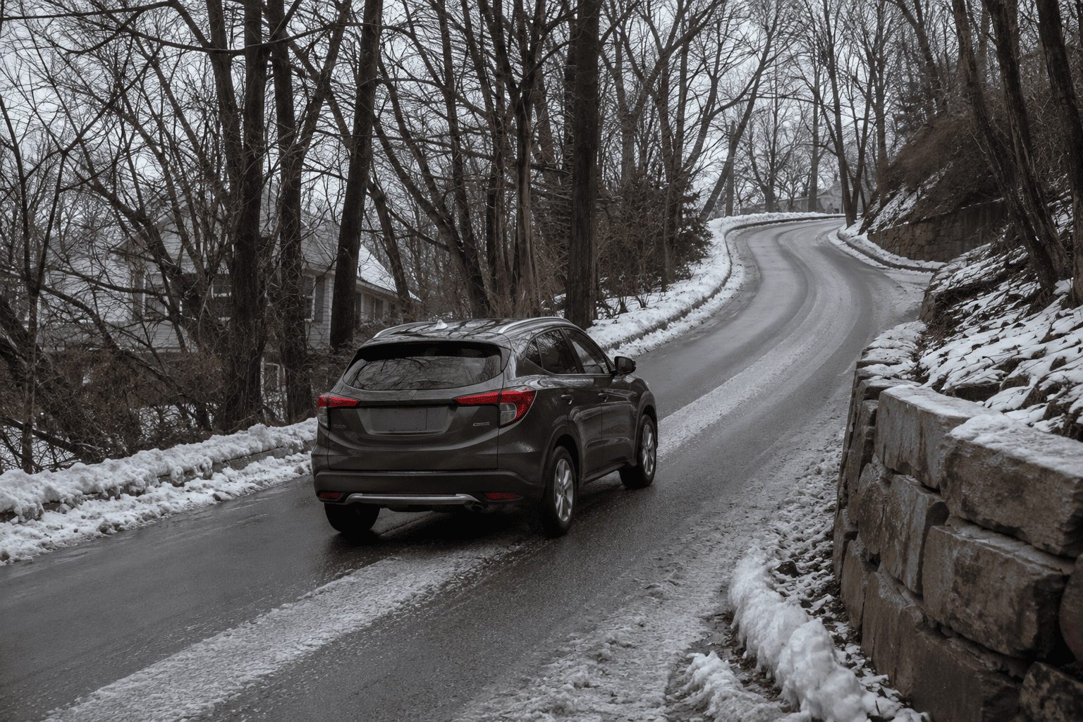 An all-wheel-drive crossover climbing a steep, tree-lined East Hill road in Englewood, New Jersey, in winter conditions